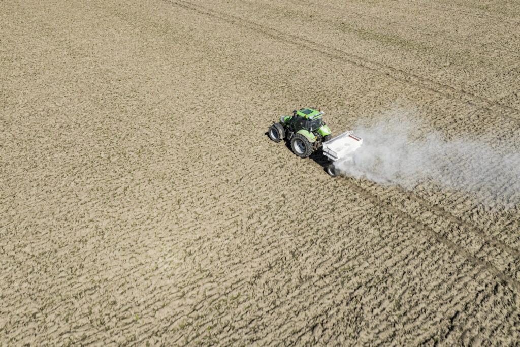 Traktor bei der Kalkausbringung auf einem Acker – Bodenverbesserung und Kalksortiment von Maier Grünlandsaat.